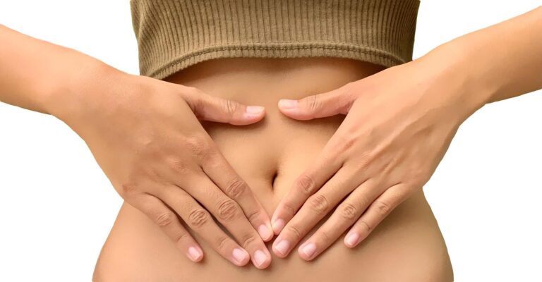 Woman with heart shaped hands on her belly.